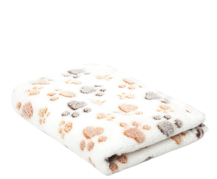 Folded white coral fleece blanket with footprints in tan, peach and grey