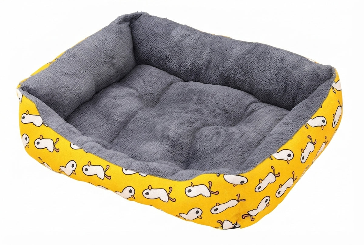 Rectangular soft dog bed in yellow duck print canvas, white cartoon ducks on the sides and a grey plush lining