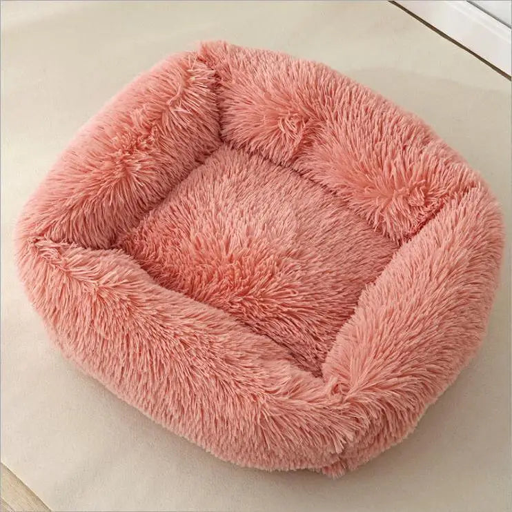 Coral pink long-plush square dog bed on a pale floor, seen from above at an angle