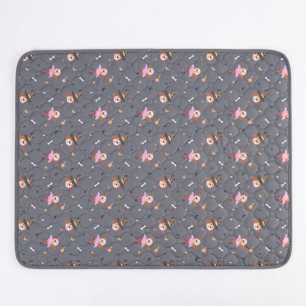 Grey quilted pet mat printed with cartoon dogs in pink and orange witch hats, moons, stars and bones