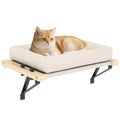 Windowsill cat bed with a cream padded cushion on a pale wood frame and black steel brackets, a ginger cat lying on it